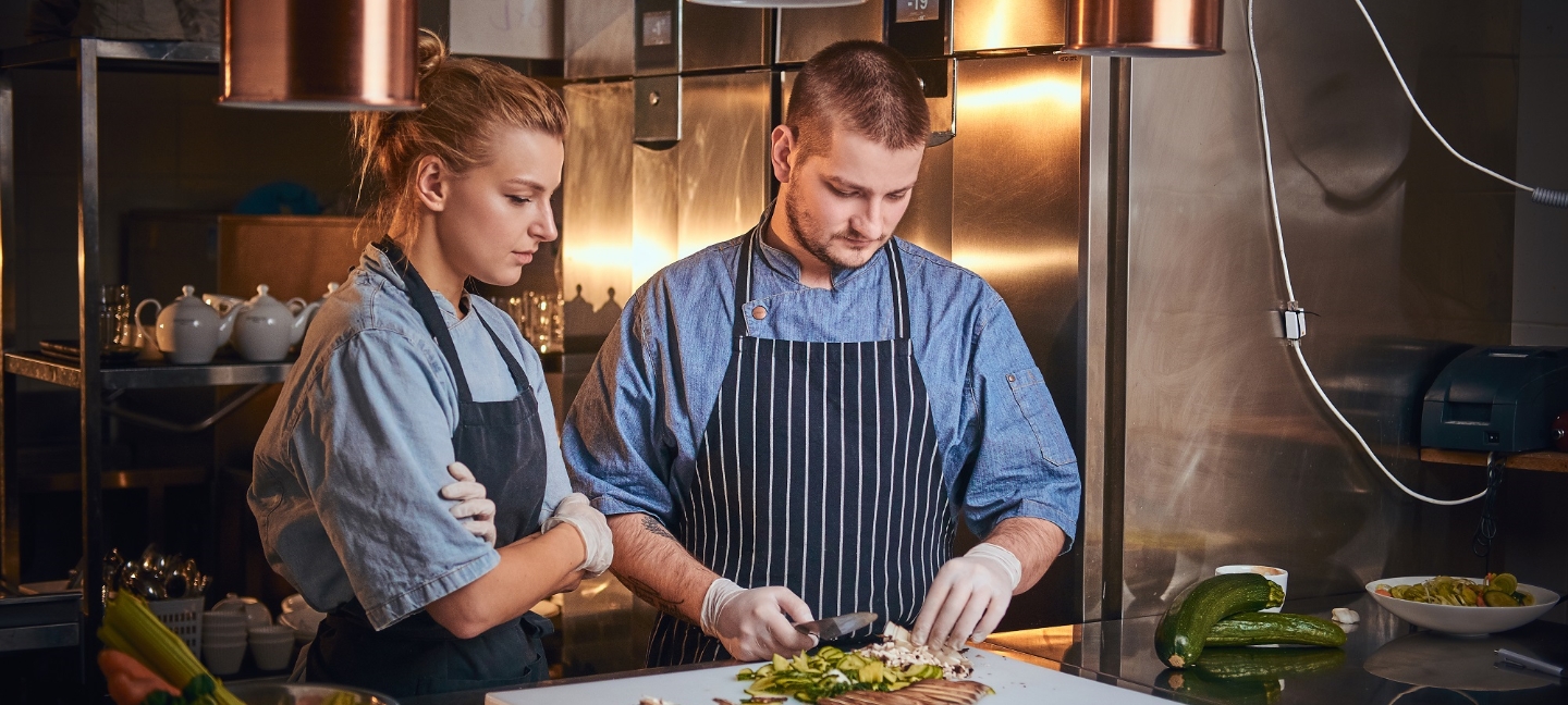 male-chef-with-assistant-standing-in-a-kitchen-pre-PCVW5CR-1.jpg